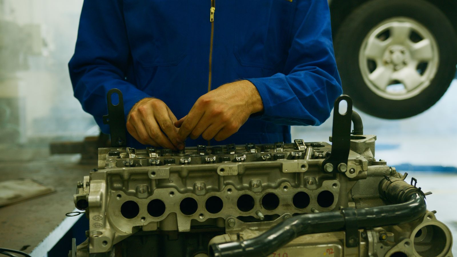 Close-up de um mecânico reparando um motor em um ambiente de garagem.